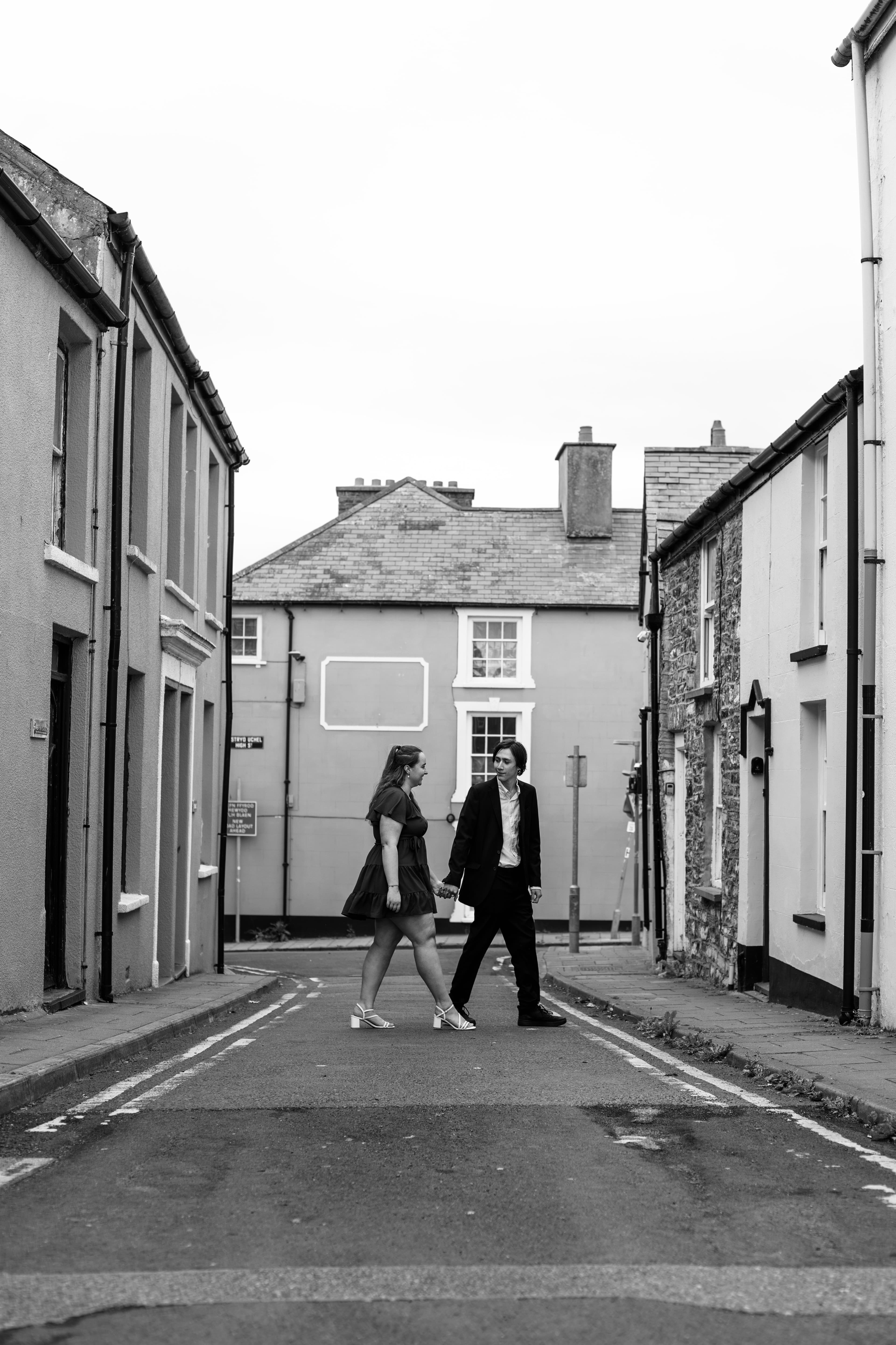 Hannah and Bradley crossing a quiet street, in black and white